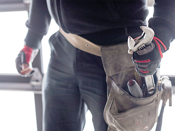 Plumber with wrench and tools in belt working on site