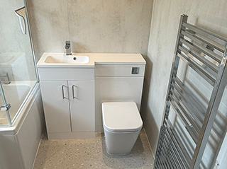 Newly installed modern bathroom with integrated basin vanity, toilet, and heated towel rail.