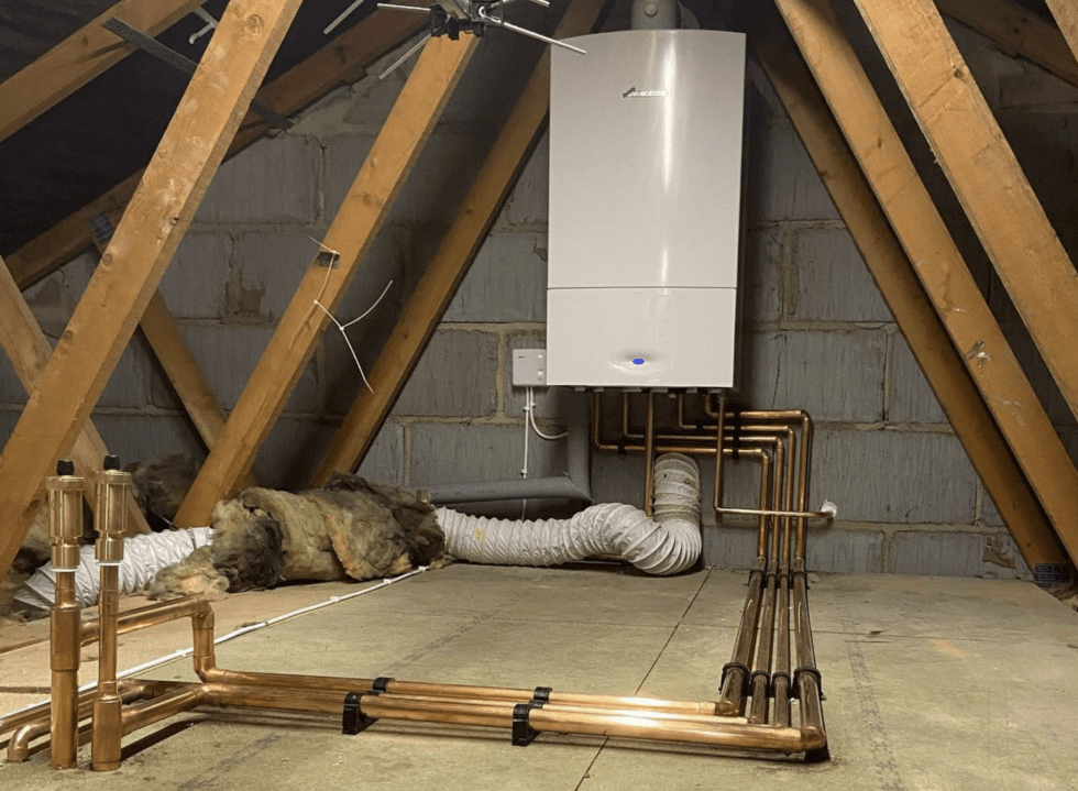 Boiler installation in a loft with copper pipes and insulation
